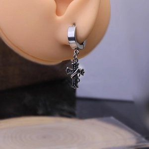Close-up of a Gothic silver cross earring on a model ear featuring punk style design