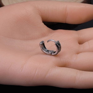 Vintage silver steel huggie earring with black embossed dragon totem on a hand model