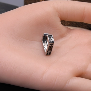 Boucle d'oreille triangle en acier argenté avec motif flamme gravé tenue à la main