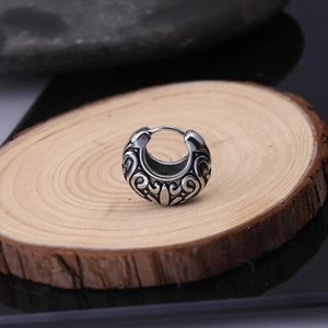 Vintage tribal pattern titanium steel hoop earring on a rustic wood slice display
