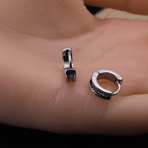 Close-up of vintage silver hoop earrings with etched dragon pattern in palm of hand