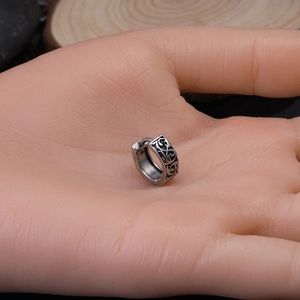 Close-up of vintage silver huggie earring with dragon totem held in palm for scale
