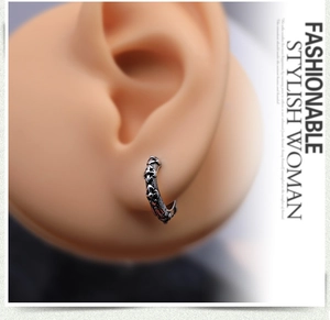Macro view of vintage silver steel hoop earring with engraved textures on a model ear