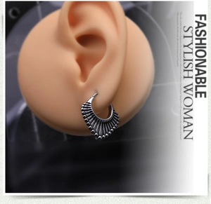 Détail de boucles d'oreilles bohèmes en argent avec texture radiale sur modèle d'oreille