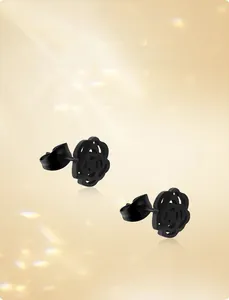 Détail macro de boucles d'oreilles roses ajourées en acier inoxydable noir mat