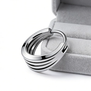 Detailed macro view of wide layered silver hoop earrings with triple band design