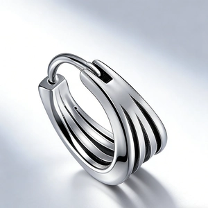 Macro view of multi-layered silver huggie earrings with textured metal stripes