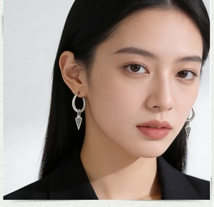 Close-up of vintage stainless steel hoop earrings with arrow point charms on model