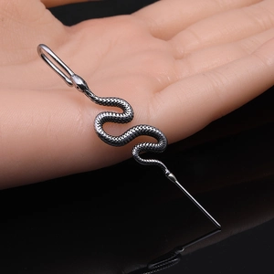 Antique silver snake industrial barbell with detailed scales on a black mirror background
