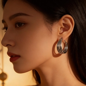 Close-up of triple-layered silver hoop earrings showing metallic shine and ribbed design