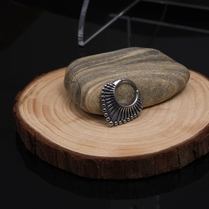Détail de la boucle d'oreille tribale en acier inoxydable en forme d'éventail sur bois