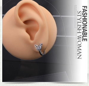 Detailed close-up of a silver butterfly hoop earring featuring clear zircon stones