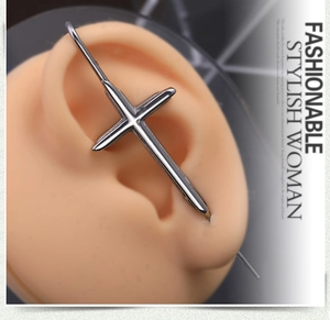 Vue rapprochée d'un piercing industriel en acier argenté avec croix sur l'oreille