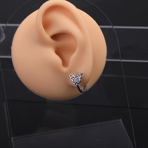 Macro shot of silver butterfly ear cuff with sparkling white zircons on silicone model