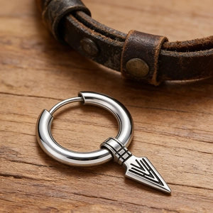 Retro stainless steel hoop earring with engraved spearhead pendant on rustic wood background
