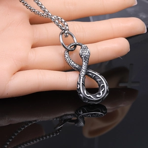 Vintage stainless steel ouroboros snake pendant necklace with a box chain on a dark background
