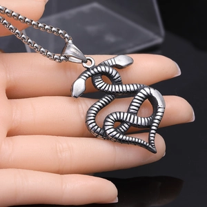 Détail d'un pendentif cœur serpent vintage en acier inoxydable avec écailles