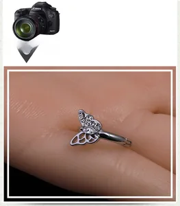 Macro shot of silver butterfly ear stud with sparkling crystals and hollowed-out wings