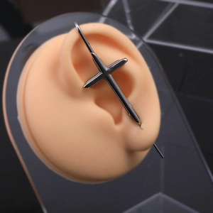 Gros plan d'un ear cuff croix en acier inoxydable noir sur un modèle d'oreille