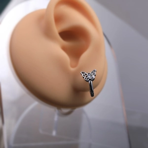 Detailed view of vintage butterfly earring with silver hollow design and zircon on ear model