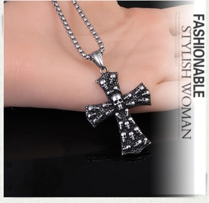 Détail du pendentif croix punk vintage avec relief de crâne et chaîne à maillons