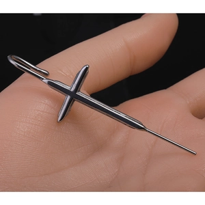 Boucle d'oreille crochet en forme de croix gothique en acier poli sur une paume