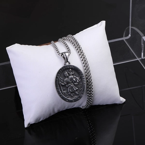 Détail du pendentif religieux Saint Christophe en acier inoxydable sur un support blanc