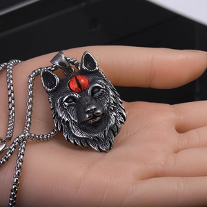 Vue détaillée du pendentif tête de loup argenté avec œil rouge sur une chaîne en acier