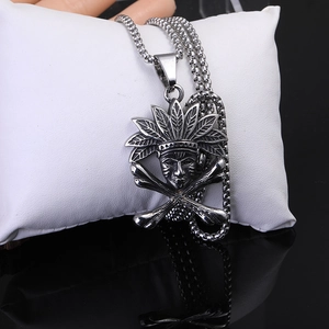 Macro d'un collier en acier titane argenté avec pendentif de chef tribal et crâne sur coussin