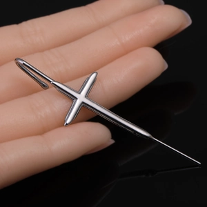 Vue macro d'un long crochet d'oreille en forme de croix en acier inoxydable argenté