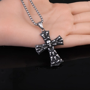 Gros plan du pendentif croix squelette punk vintage avec chaîne sur main d'exposition