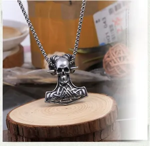 Vue macro d'un pendentif tête de bélier punk vintage et marteau de Thor vieilli