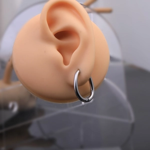 Close-up of minimalist silver Mobius twist hoop earring on a silicone ear model display