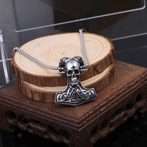 Gros plan du pendentif viking argenté avec crâne et marteau de Thor sur des rondins