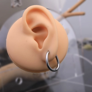 Silver stainless steel Mobius twist hoop earrings shown on a model for scale