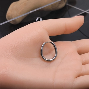 Detailed view of polished silver twisted Mobius hoop earrings on a model hand