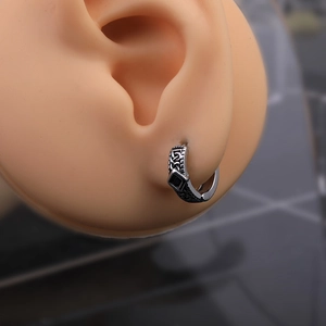Close-up of vintage stainless steel hoop earring with Celtic knots and black stone