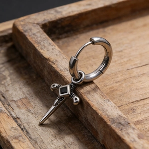 Macro detail of gothic sword drop earring with black stone on vintage wood background
