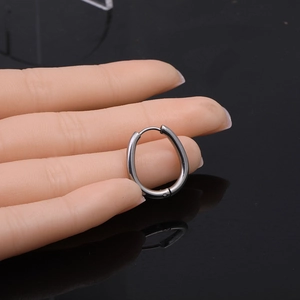 Polished silver Mobius twist hoop earrings shown on a model hand with reflective background
