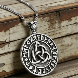 Gros plan du pendentif viking avec nœud de Triquetra et runes nordiques sur bois rustique