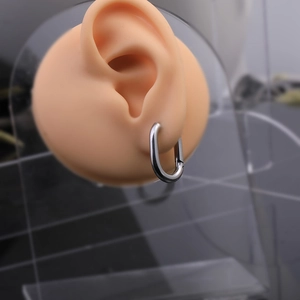 Detailed view of U-shaped stainless steel hoop earring on display stand