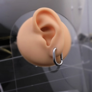 Close-up of polished silver U-shaped Mobius twist hoop earring on a model ear