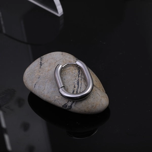 Detailed view of silver Mobius twist hoop earring on a natural stone with reflection