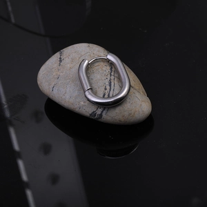 Macro detail of polished stainless steel Mobius twist hoop earring on stone background