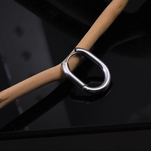 Detailed macro view of silver oval Mobius twist earrings on a wood branch with reflections