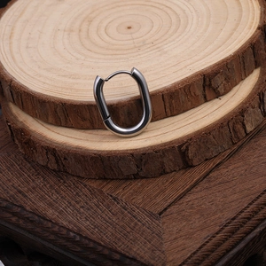 Polished silver Mobius twist hoop earrings displayed on a natural wood ring surface