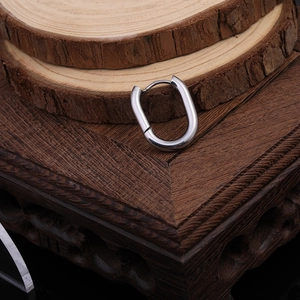 Detailed view of silver Mobius twist hoop earrings on a minimalist wooden display stand
