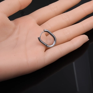 Detail view of a silver Mobius twist hoop earring displayed on a model hand for size reference