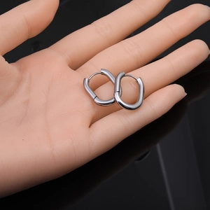 Macro shot of polished silver Mobius twist hoop earrings held by hand for size reference