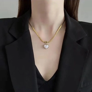 Shell heart pendant necklace with gold snake chain worn on a stylish black blazer